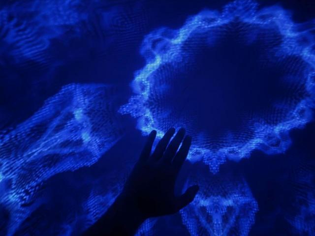 A hand reaching toward a fractal pattern